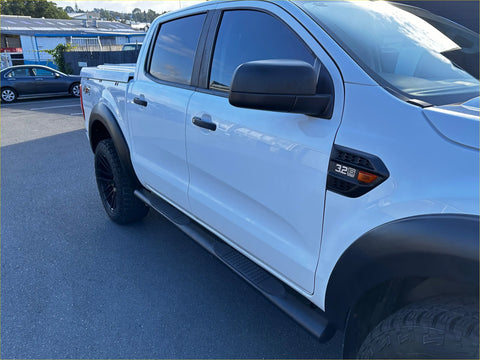 White ford ranger with black stainless steel 4 inch oval tube running board and rugged tires visible from the back