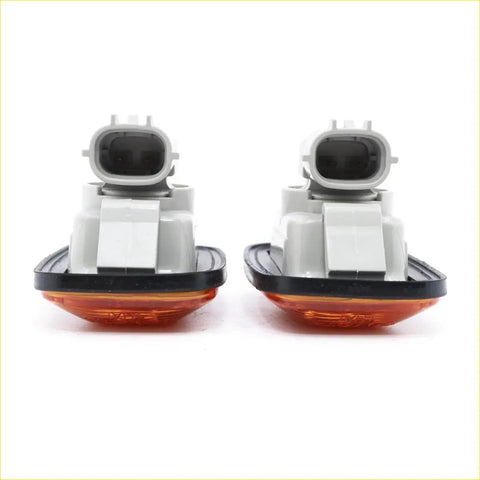 A pair of amber plastic side turn signal lights with gray connectors and black gaskets for toyota hilux 1997-2006