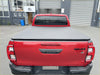 Back view of a red toyota hilux 2015-2020 sr5 with a black soft tonneau cover over the bed