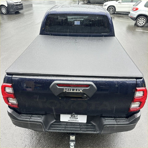 Dark blue toyota hilux 2015-2020 sr5 with gray hard-shell soft tonneau cover shown from the back side