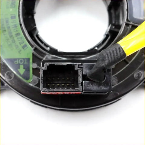 Black plastic spiral cable clock spring with yellow-handled tool in connector port for mitsubishi delica d5 back side