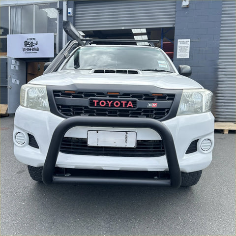 White toyota hilux gr pickup with matte black stainless steel nudge bar, black bumper guard, and roof rack