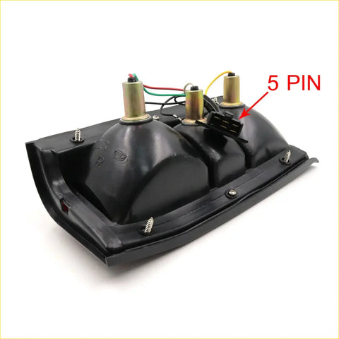 Backside of a black plastic tail light for Mitsubishi L200 Strada Colt Dodge Ram 50 with three gold bulb sockets and 5-pin connector