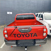 Back view of a red Toyota hilux 2021 with a textured black tailgate cover featuring black Toyota logo and silver trim
