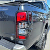 Back view of a matte black taillight cover with modern angular design on a mitsubishi triton 2019-2023 pickup truck