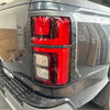 Black matte taillight cover for mitsubishi triton 2024 with red and clear lens in rugged gray plastic bezel back side view