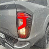 Red and amber led taillight cover with a modern angular design on the back of a matte black nissan navara 2021+ pickup