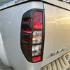 Black plastic taillight cover with red and clear lenses on silver nissan navara d40 pickup truck back side