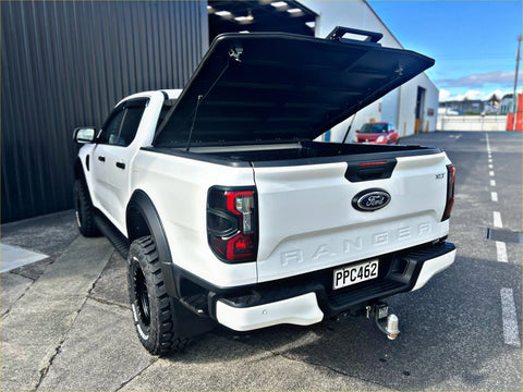 White ford ranger pickup truck with black accents and lifted suspension featuring tomahawk hardlid next gen ranger 2022-current