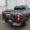 Dark gray toyota hilux sr5 double cab with black tomahawk aluminium hardlid and off-road tires shown from the back side